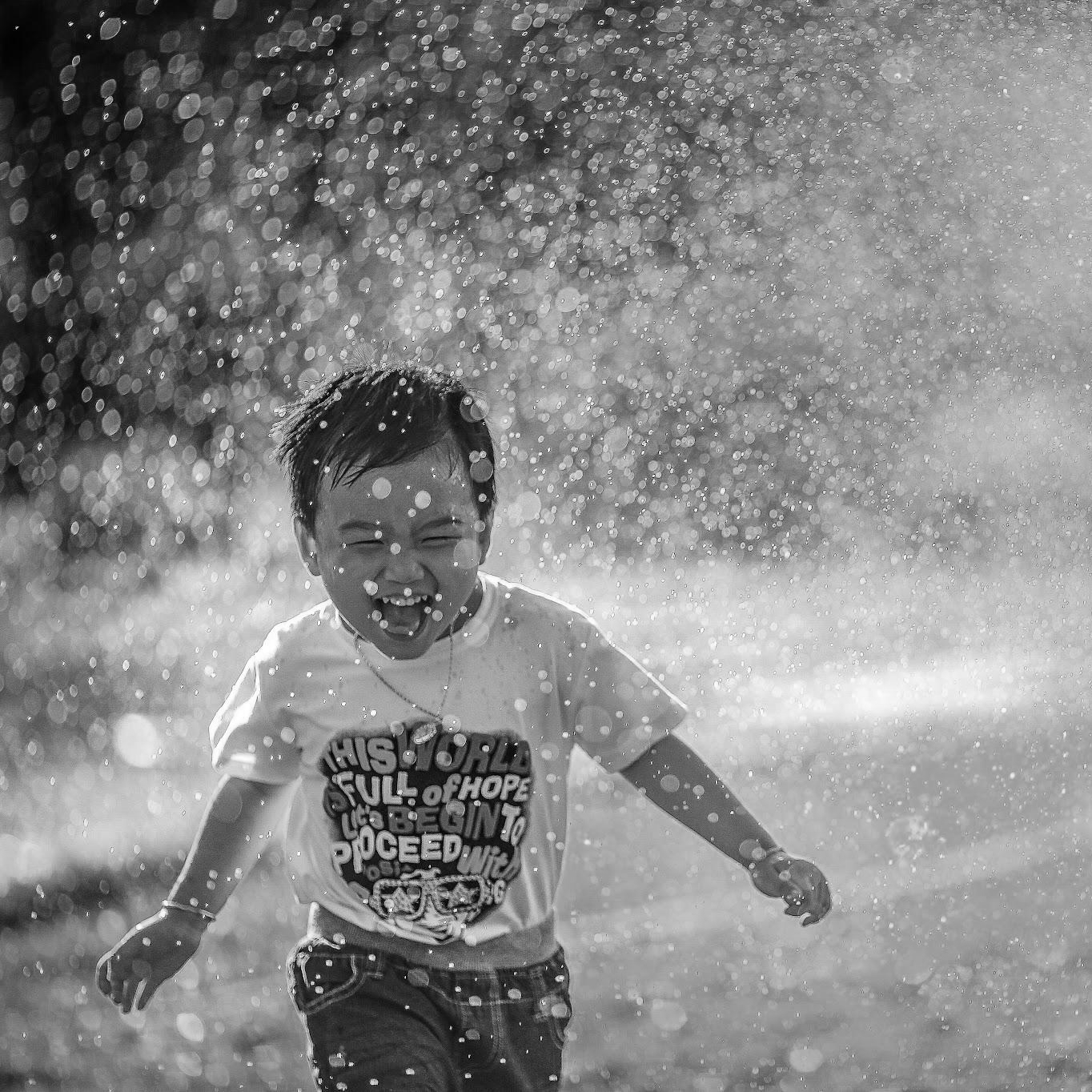 happy child running through the spray of a sprinkler
